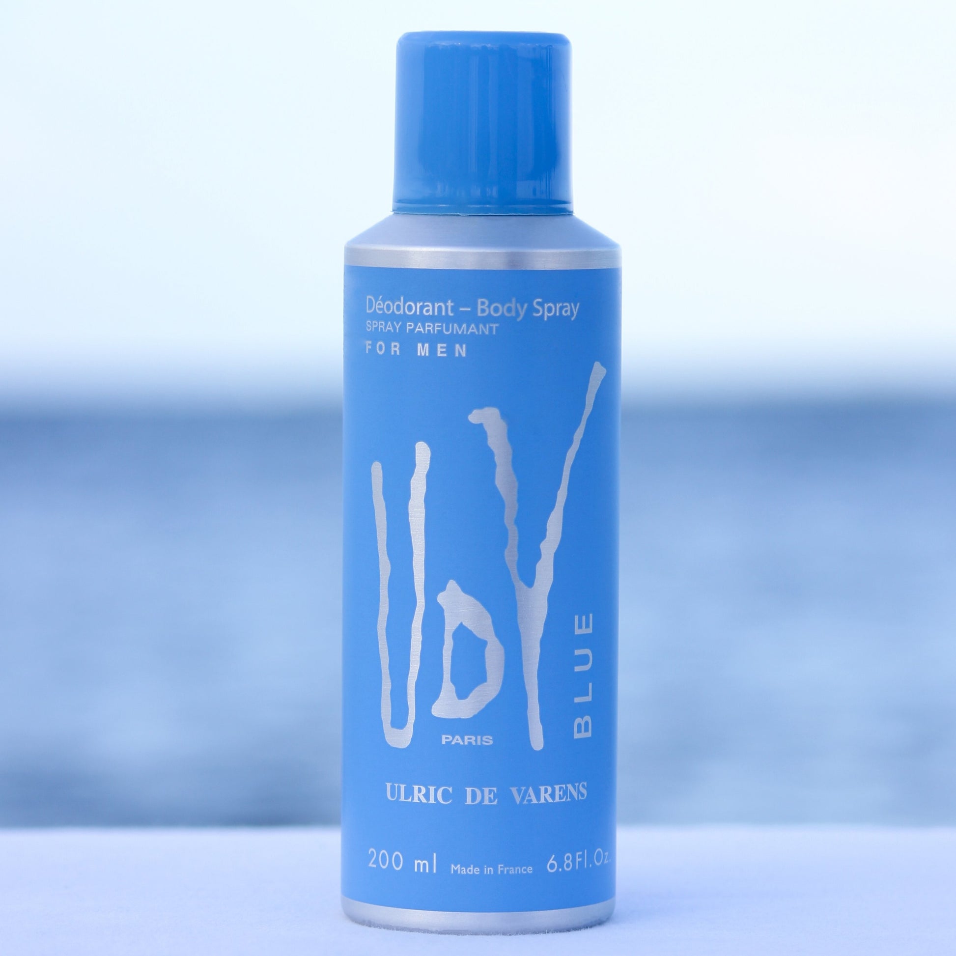 Ulric De Varens UDV Blue men's perfume scented deodorant 6.4 oz in front of beach